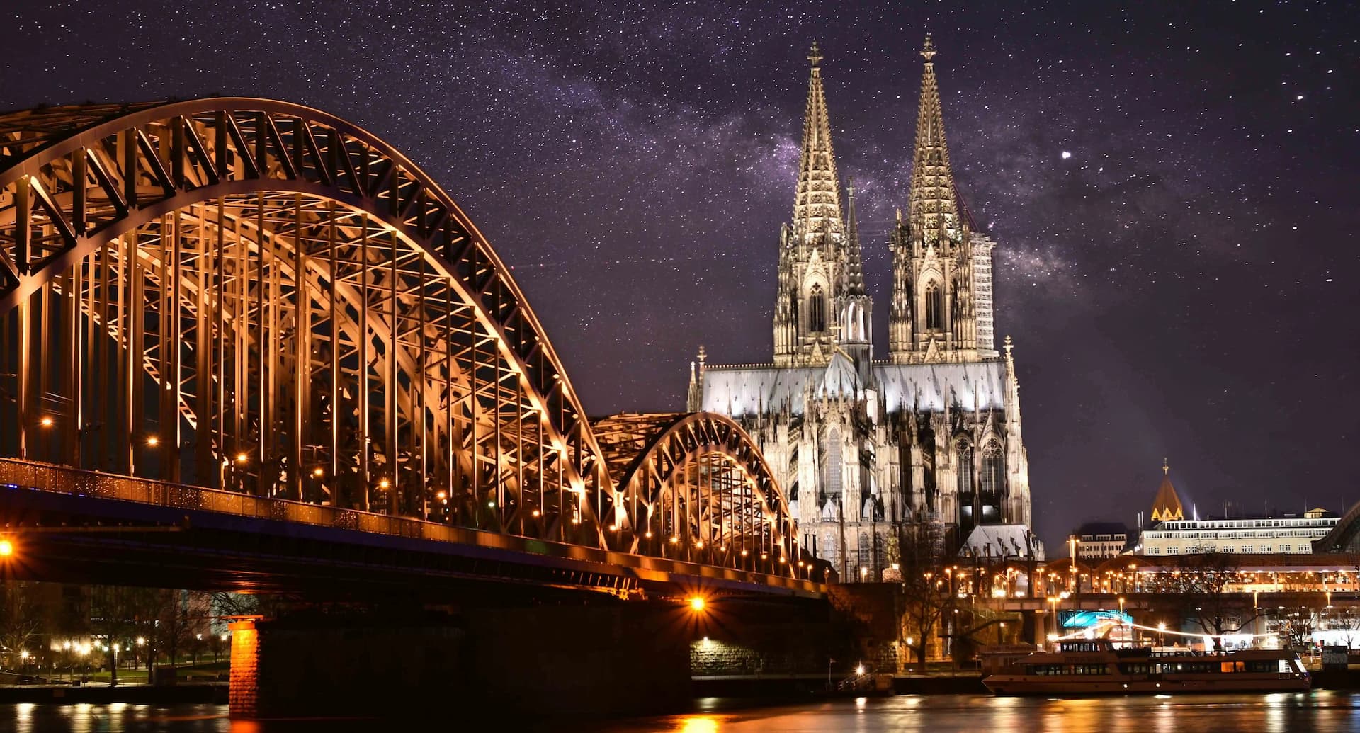 A night view of a bridge and cathedral with a starry sky background.